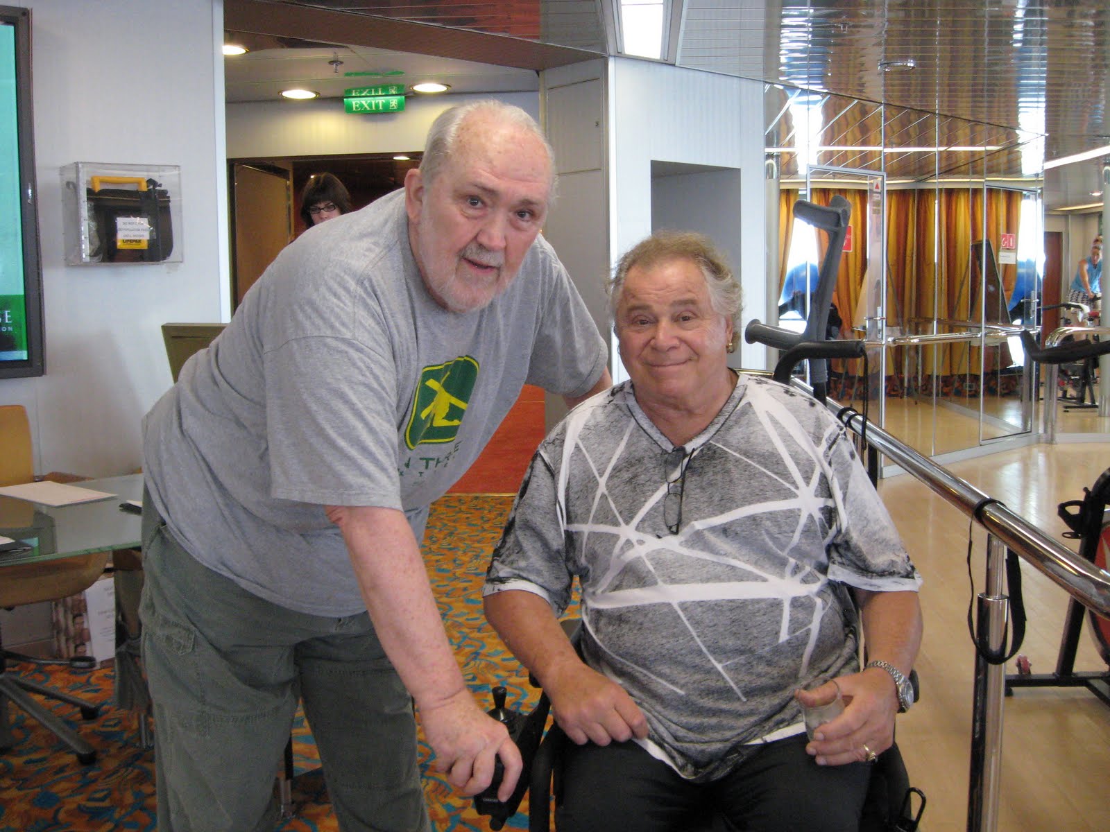 Art Metrano smiling while sitting on a wheelchair in a gray shirt and black pants